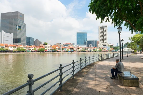 Homme assis sur un banc public au bord de la rivière — Photo