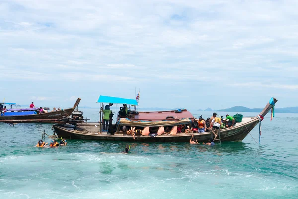 Turisté se šnorchlováním dlouhých člunů v čisté mořské vodě — Stock fotografie