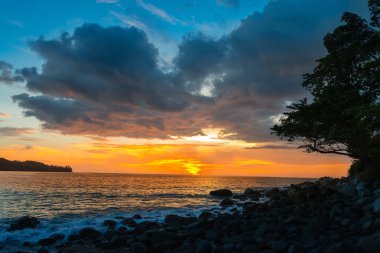 Sunset bulvarında bir kayalık sahil plaj turuncu ve mavi bulutlar ile
