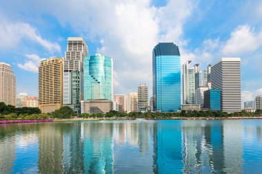 mavi gökyüzünün altında göl yansıması ile modern şehir manzarası