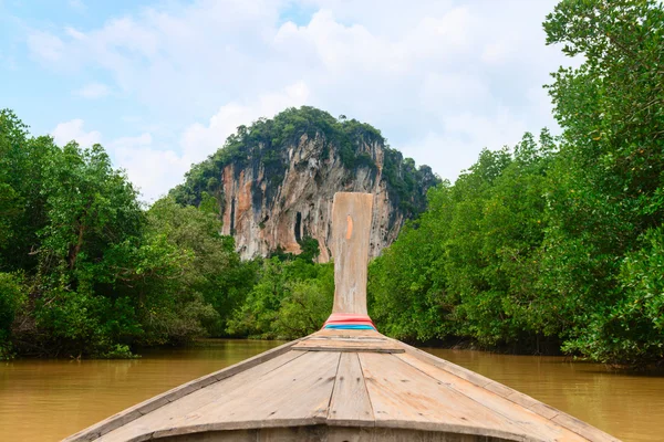 Wooden boat on a river with mangroves and big limestone cliff — Stock Photo, Image