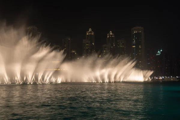 Fontes iluminadas realizando efeitos dramáticos ao longo da praia urbana — Fotografia de Stock