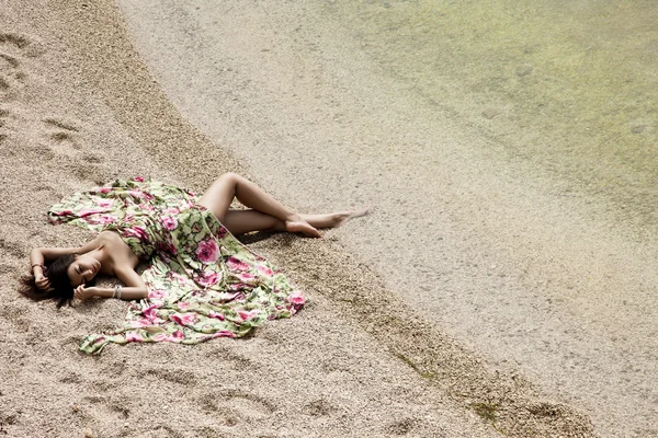Девушка, лежащая на песке у моря — стоковое фото