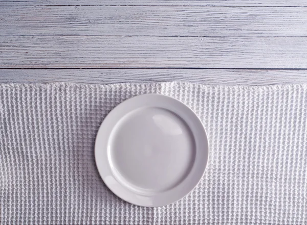 Пустая тарелка на скатерти на деревянном столе — стоковое фото