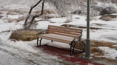 Buzlu ve karlı, dikey bir yerde, bir sokak lambasının altında boş bir bank.