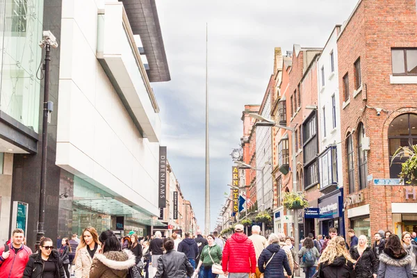 Люди, идущие по Генри-стрит со шпилем на заднем плане, Дублин — стоковое фото