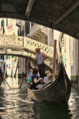 Venedik, İtalya - 5 Ağustos 2016: Kanalda gondolların tadını çıkaran turistler. Gondollar şehirdeki en popüler ve romantik ulaşım araçlarıdır..