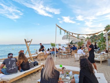 Golfe Juan, Fransa - 26 Haziran 2021: İnsanlar gün batımında plajın keyfini çıkarıyorlar. Fransız Rivierası yaz boyunca Avrupa 'nın en önemli tatil beldelerinden biridir..