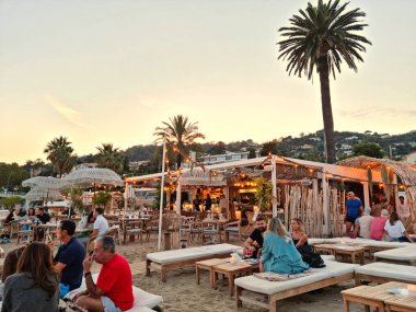 Golfe Juan, Fransa - 18 Eylül 2021: İnsanlar gün batımında plajın keyfini çıkarıyorlar. Fransız Rivierası yaz boyunca Avrupa 'nın en önemli tatil beldelerinden biridir..