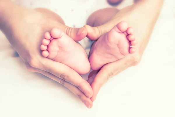Pies de bebé en las manos de la madre — Foto de Stock