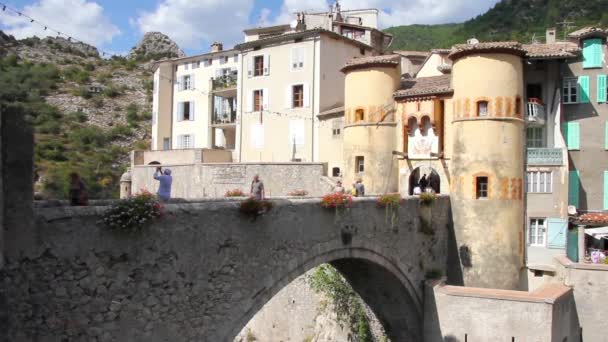 Personas caminando en la entrada de la ciudad medieval de Entrevaux, al sur de Francia — Vídeo de stock