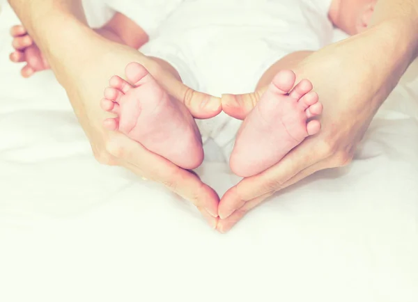 Mamma håller barnets fötter — Stockfoto