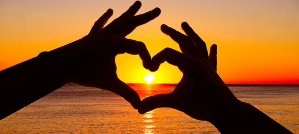 Silhouette hand in heart shape and sunrise over the ocean — Stock Photo, Image