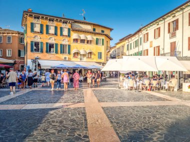 Sirmione, İtalya - 21 Temmuz 2024: Şehir merkezinde yürüyen insanlar. Garda Gölü kıyısında yer alan şehir, Scaligero kalesi ile su üzerinde ünlüdür..