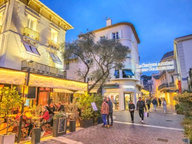 Sainte Maxime, Fransa - 22 Şubat 2025: Geceleri şehir merkezinde yürüyen insanlar. Eski kasaba dükkanları, pazarları, restoranları, barları ve kafeleri ve limanı olan turistik bir yer..