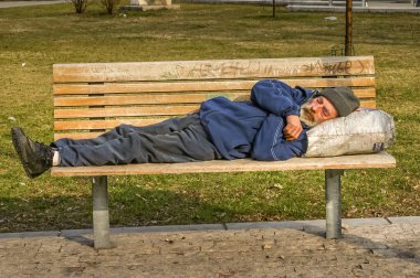 Budapeşte, Macaristan - 25 Mart 2006: Evsiz yaşlı bir adam bankta uyuyor. Yoksulluk nüfus sayımı ülkede hassas bir konu..