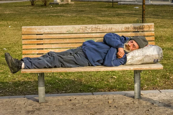 Budapeşte, Macaristan - 25 Mart 2006: Evsiz yaşlı bir adam bankta uyuyor. Yoksulluk nüfus sayımı ülkede hassas bir konu..