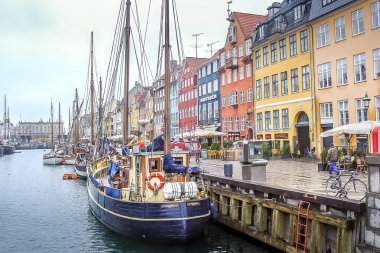 Kopenhag, Danimarka - 30 Mars 2006: Nyhavn kanalında yürüyen insanlar. New Harbour, Kopenhag 'da 17. yüzyıla ait renkli evi (Nordic Tobermory), tarihi gemileri ve canlı, yaya rıhtımı ile ünlü bir liman bölgesi.