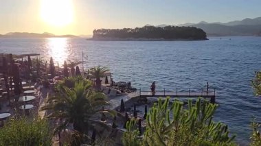 Dubrovnik, Hırvatistan - 27 Temmuz 2025: Mercan plajının tadını çıkaran insanlar. Kulübün Daksa adası manzarası var ve günbatımını izlemek için mükemmel bir yer..