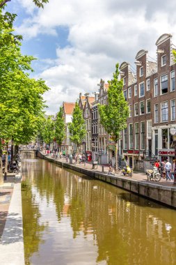 Amsterdam, Hollanda - 31 Mayıs 2014: Amsterdam 'da bir kanalda yürüyen turistler. Amsterdam Hollanda 'nın başkentidir ve kanallar ve limanlar şehir yüzeyinin dörtte birini doldurur..