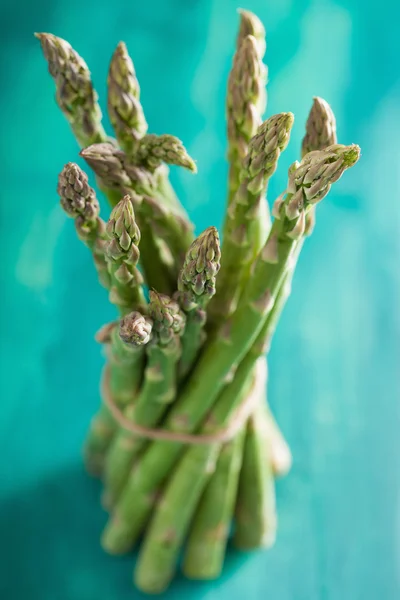 Bunch of fresh asparagus on turquoise background — Stock Photo, Image