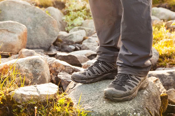 hiker standing on rock, legs in boots