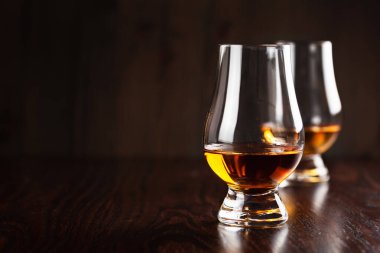 Koyu kahverengi arka planda bir bardak viski ruhu brendisi.