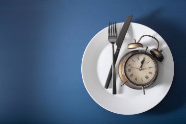 concept of intermittent fasting, ketogenic diet, weight loss. fork and knife on a plate and alarmclock clipart