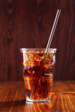 Bir bardak soğuk kola, ahşap zemin üzerinde buz.