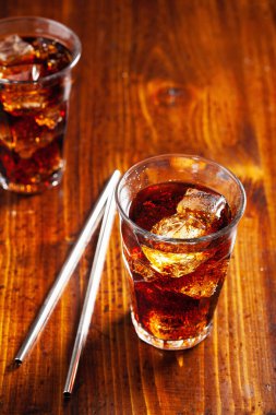 Bir bardak soğuk kola, ahşap zemin üzerinde buz.