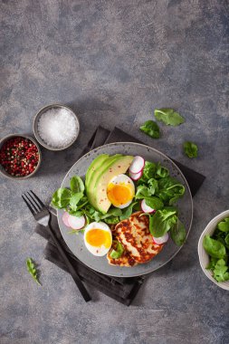 Sağlıklı keto paleo diyeti kahvaltısı: haşlanmış yumurta, avokado, halloumi peyniri, salata yaprakları.