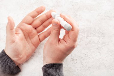 Erkek elleri kan şekeri ve keton seviyelerini glikoz ölçmek için parmak üstüne mızrak kullanır. İlaç diyabeti keto diyet sağlık hizmetleri evde
