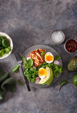 Sağlıklı keto paleo diyeti kahvaltısı: haşlanmış yumurta, avokado, halloumi peyniri, salata yaprakları.