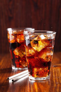 Bir bardak soğuk kola, ahşap zemin üzerinde buz.