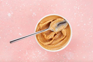 Pembe arka planda fıstık ezmesi.