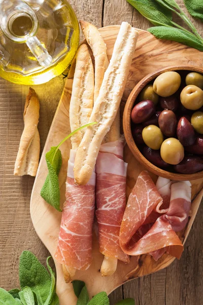 Italian prosciutto ham grissini bread sticks olive oil — Stock Photo, Image