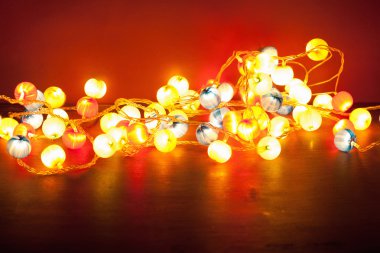 kırmızı bir arka plan üzerinde yanan Noel ışıkları