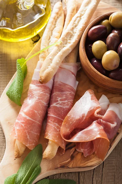Italian prosciutto ham grissini bread sticks olive oil — Stock Photo, Image