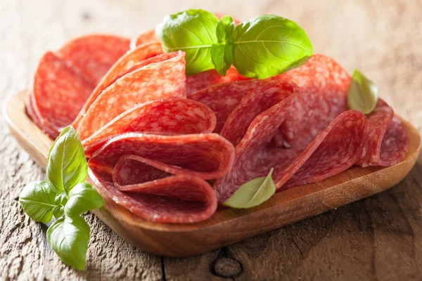 Salami slices in wooden plate — Stock Photo, Image