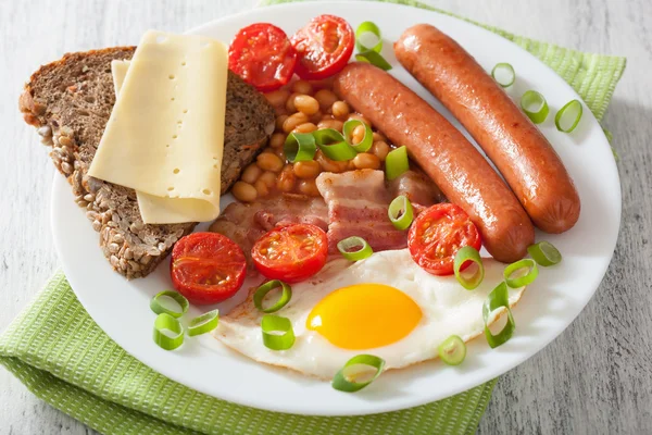 English breakfast with fried egg sausages bacon tomatoes beans — стоковое фото