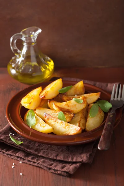 Cunei di patate al forno in piatto su tavolo rustico marrone — Foto Stock