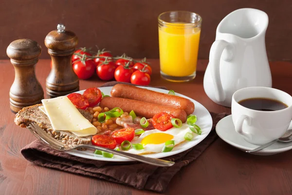 English breakfast with fried egg sausages bacon tomatoes beans — стоковое фото