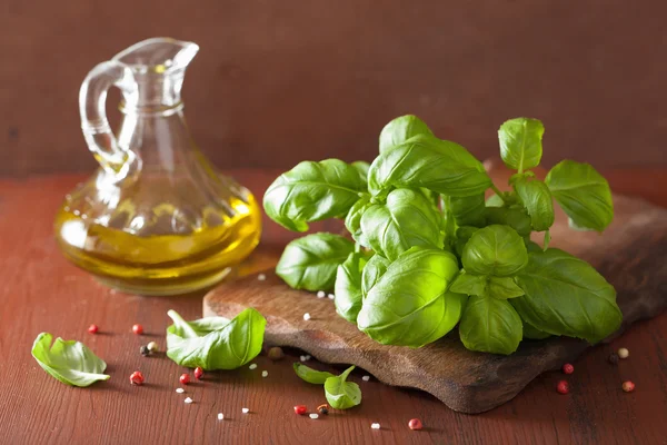 Hojas de albahaca fresca hierba y aceite de oliva en bacgkround de madera — Foto de Stock