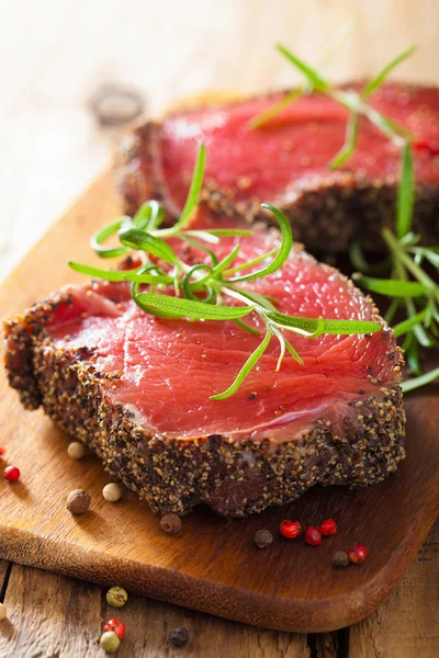 Raw beef steak with spices and rosemary on wooden background — Stock Photo, Image