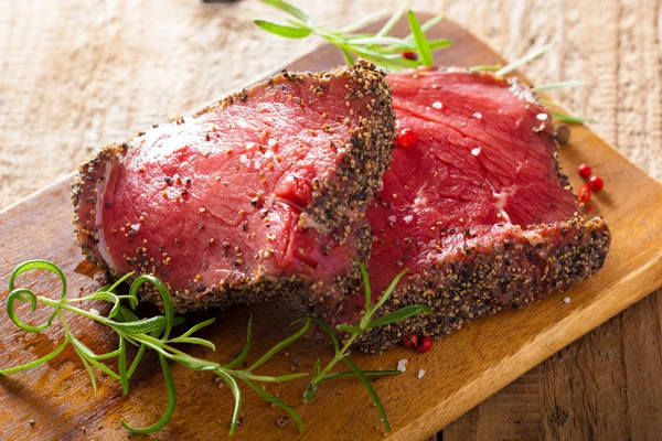 Syrové hovězí steak s kořením a rozmarýnem na dřevěné pozadí — Stock fotografie