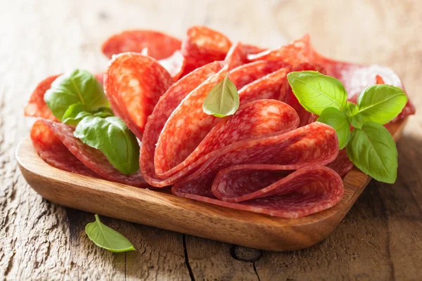 Rebanadas de salami en plato de madera — Foto de Stock