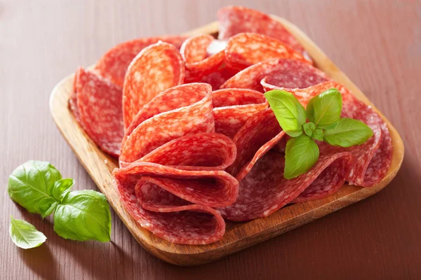 Salami slices in wooden plate — Stock Photo, Image