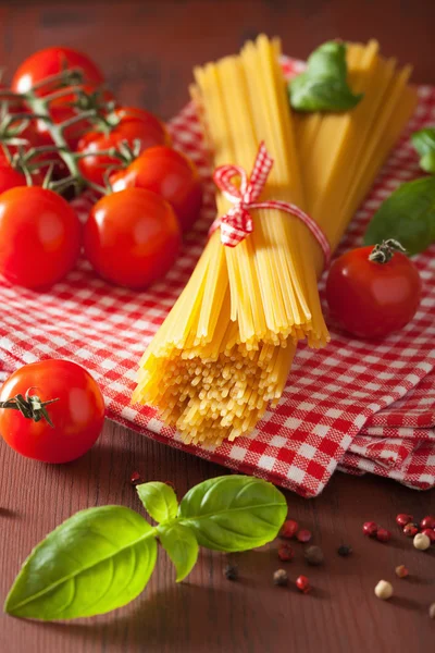Espaguete cru macarrão manjericão tomates. cozinha italiana em ki rústico — Fotografia de Stock