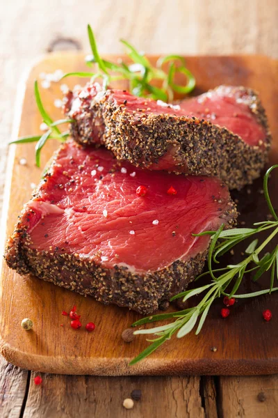 Filete de res crudo con especias y romero sobre fondo de madera —  Fotos de Stock