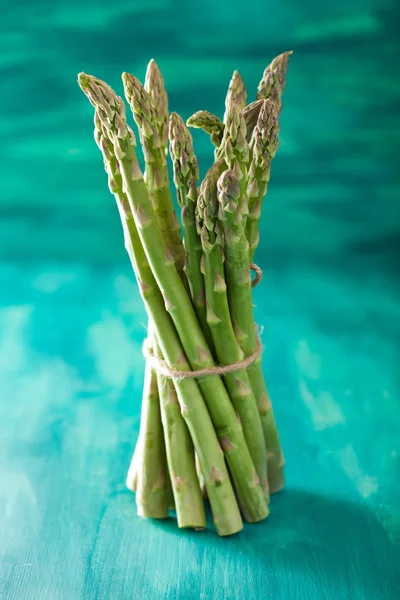 Bunch of fresh asparagus on turquoise background — Stock Photo, Image